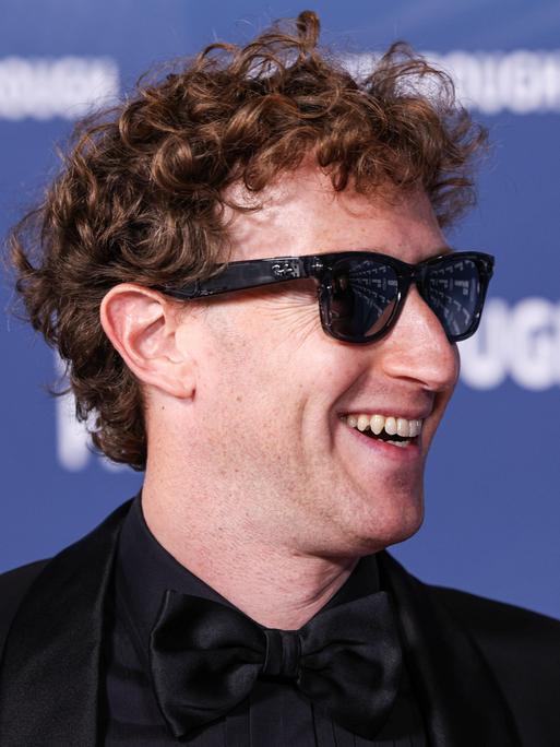 Der Meta-CEO Mark Zuckerberg trägt eine dunkel getönte Sonnenbrille, lächelt und schaut nach rechts.