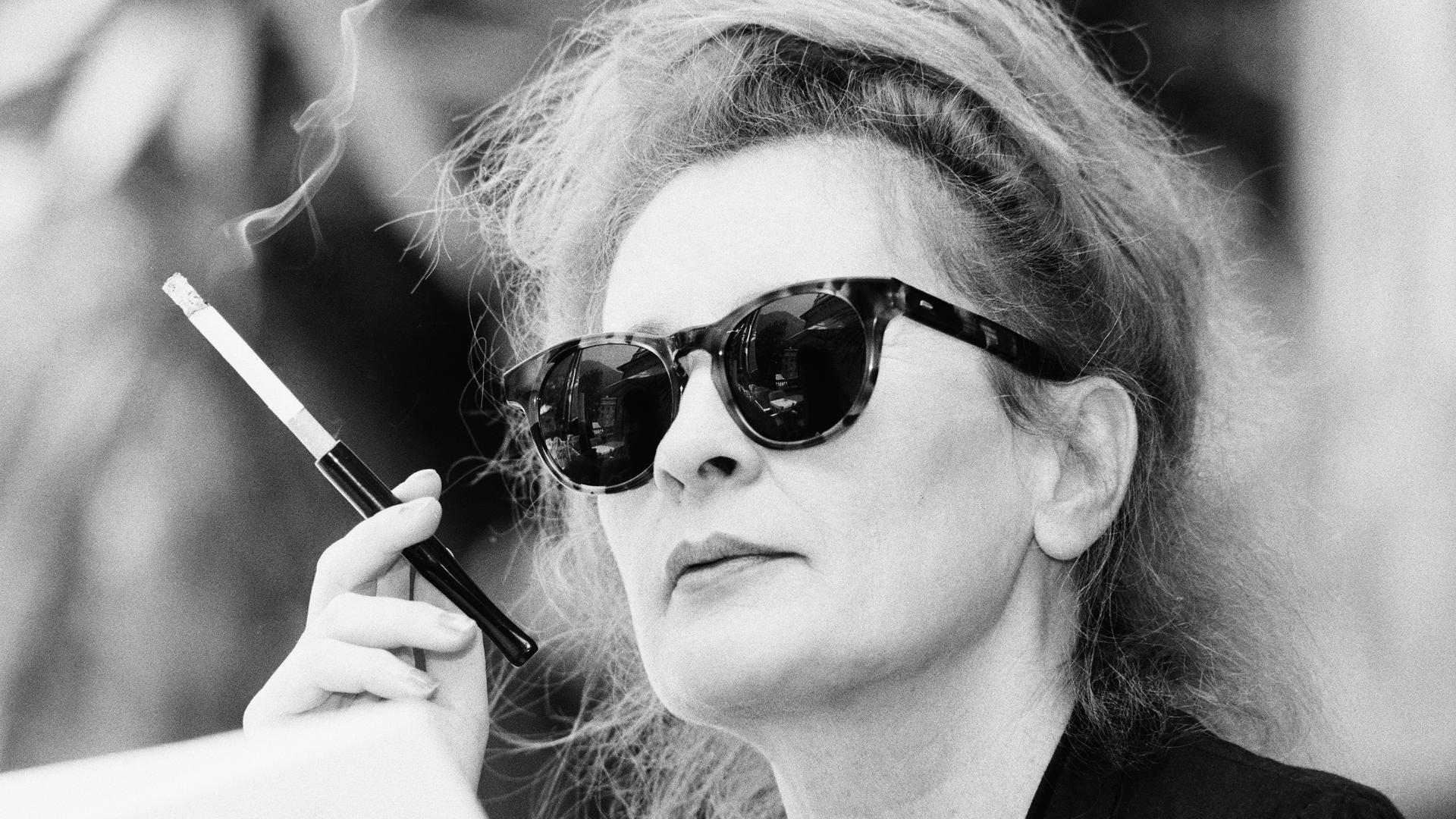 Ingrid Caven mit großer Sonnenbrille und einer Zigarette im Zigarettenhalter