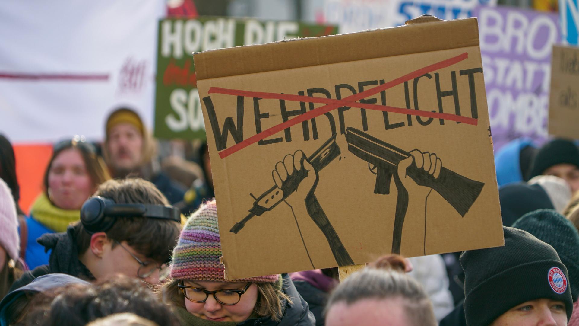 Ein selbst gestaltetes Plakat mit dem Wort Wehrpflicht, das mit rot durchgestrichen ist, wird während eines Protestes in die Höhe gehalten