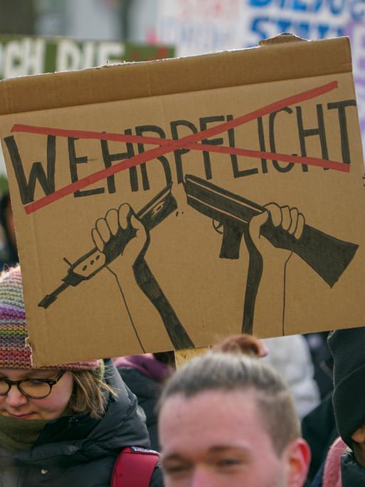 Ein selbst gestaltetes Plakat mit dem Wort Wehrpflicht, das mit rot durchgestrichen ist, wird während eines Protestes in die Höhe gehalten