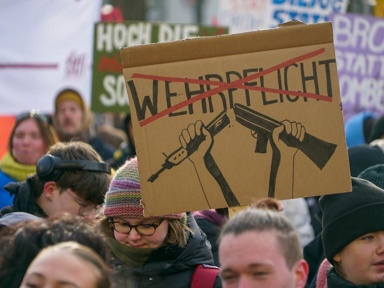 Ein selbst gestaltetes Plakat mit dem Wort Wehrpflicht, das mit rot durchgestrichen ist, wird während eines Protestes in die Höhe gehalten