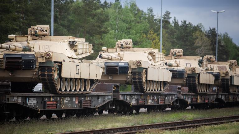 Panzer stehen aufgereit auf einem Bahn-Wagon.