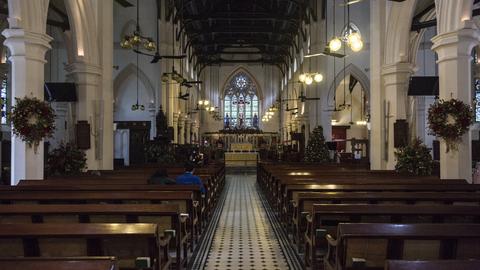 Innenraum einer katholischen Kirche in Hongkong. Zwei Personen sitzen nebeneinander in einer Bank.