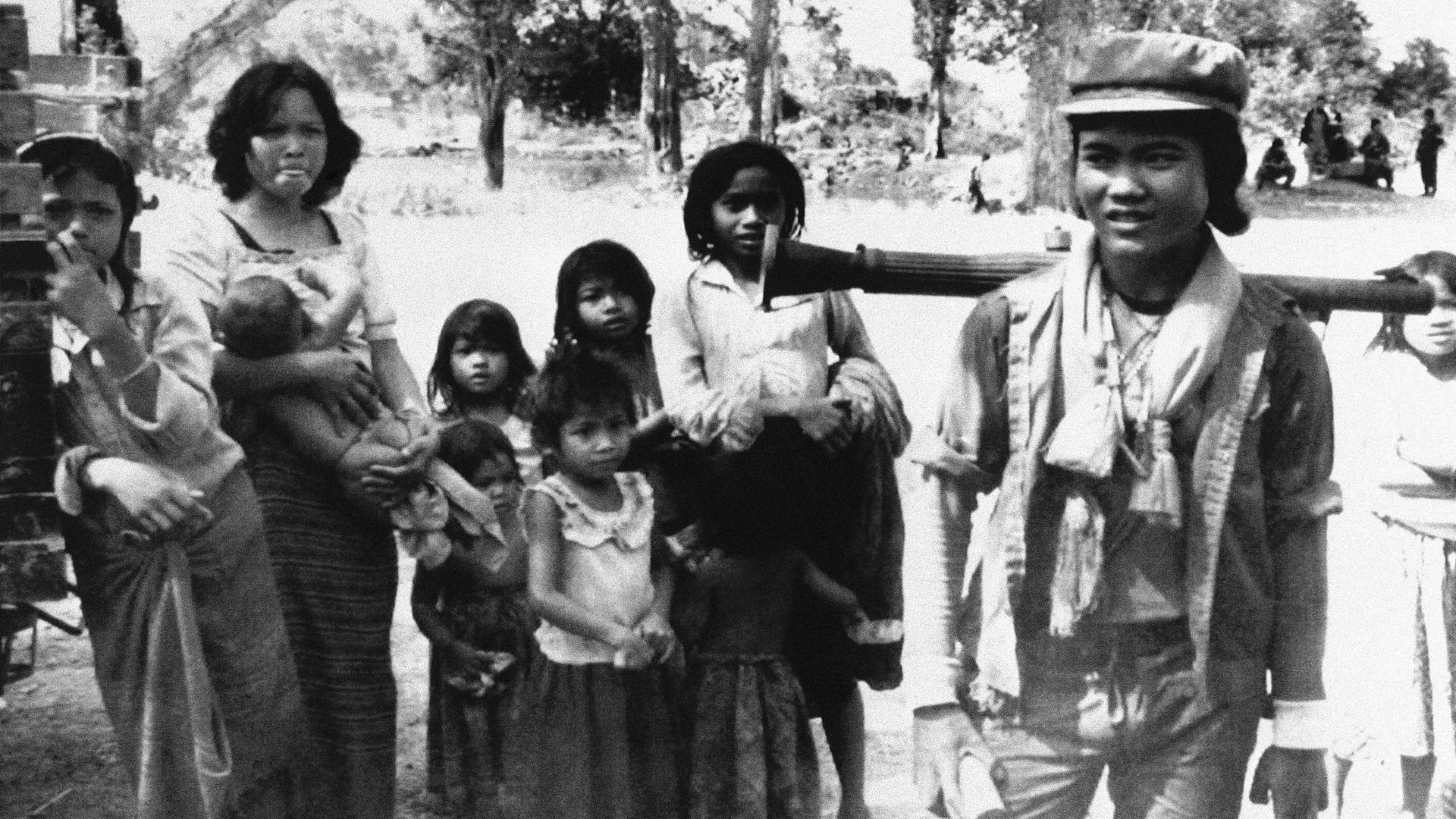 Ein Kämpfer der Roten Khmer mit einem Granatwerfer auf dem Rücken, umringt von Bewohnerinnen und Bewohnern eines Dorfes in der Provinz Banteay Meabcgey.