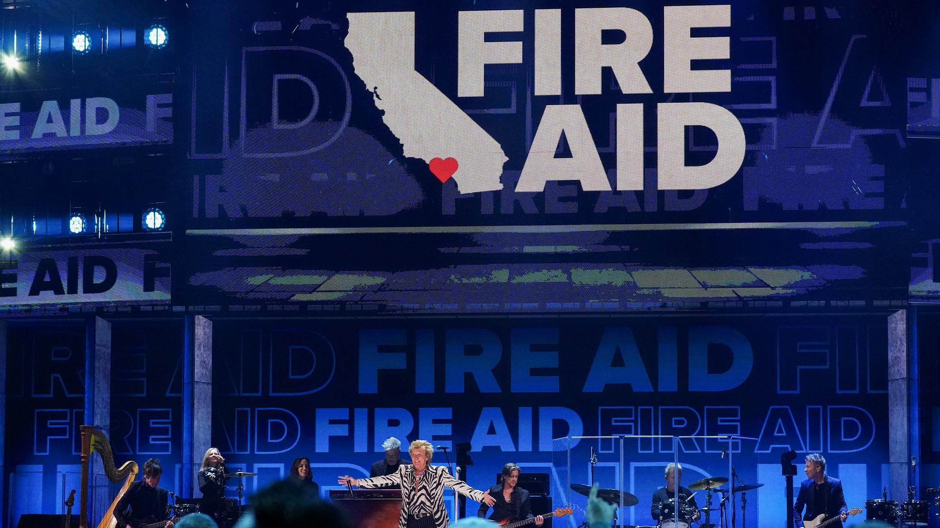 Der Musiker Rod Stewart steht auf einer Bühne, im Hintergrund der Schriftzug "FireAid.