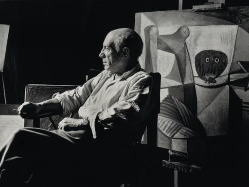 Pablo Picasso sitzt rauchend in seinem Atelier.