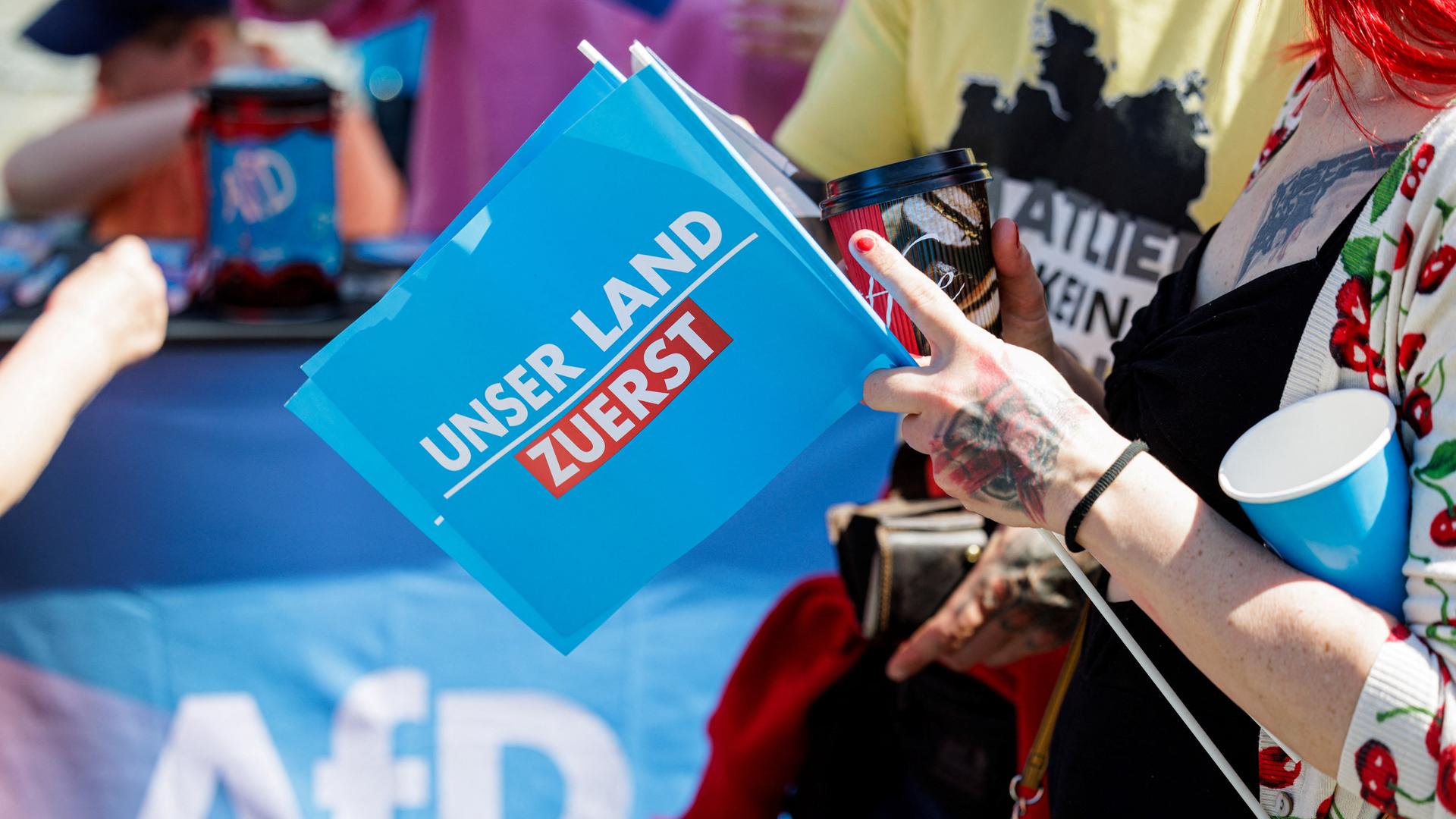 Ein Anhänger der Alternative für Deutschland (AfD) hält eine kleine Fahne mit dem Slogan „Unser Land zuerst“ während einer Wahlkampfveranstaltung für die bevorstehenden Wahlen zum Europäischen Parlament und vor den sächsischen Kommunal- und Landtagswahlen in Dresden.