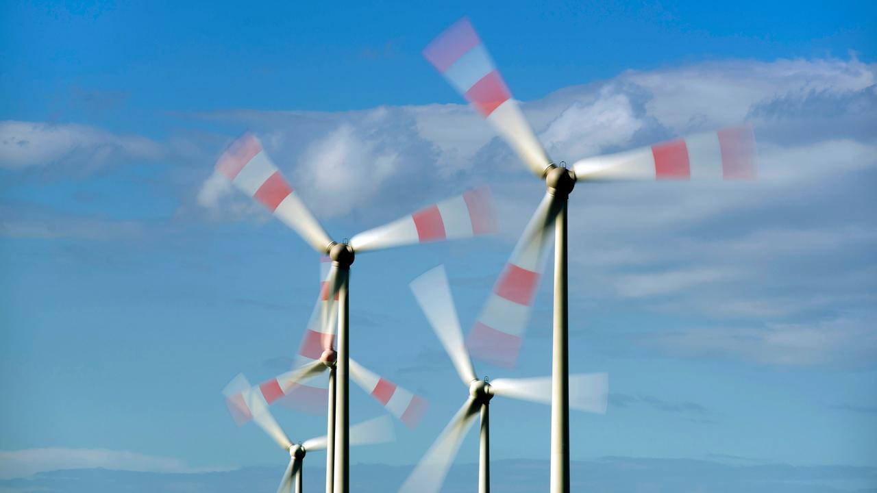 Windkrafträder drehen sich vor blauem Himmel.