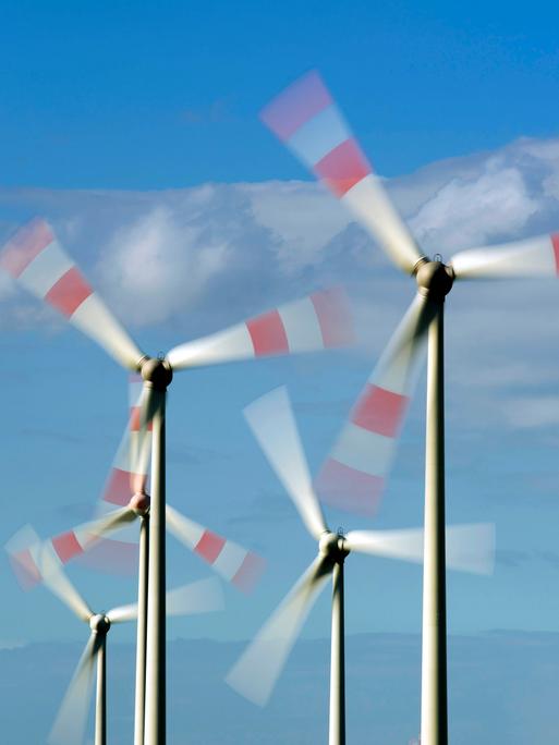 Windkrafträde drehen sich vor blauem Himmel.