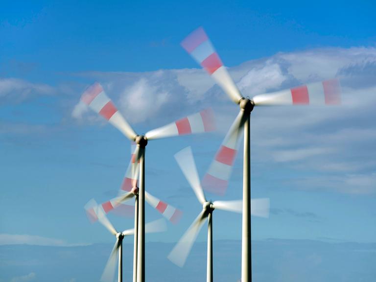 Windkrafträde drehen sich vor blauem Himmel.