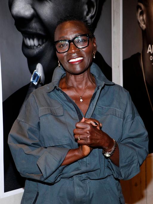 Auma Obama lacht in die Kamera. Sie trägt eine blaue Bluse und eine schwarz umrandete Brille.