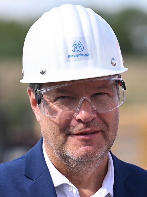 Der Bundesminister für Wirtschaft und Klimaschutz Robert Habeck mit einem Helm bei seinem Besuch bei der Thyssenkrupp-AG in Duisburg am 26. Juli 2023. Anlass des Besuchs ist das Fördersiegel der Bundesregierung für das Dekarbonisierungsprojekt "tkH2Steel".
