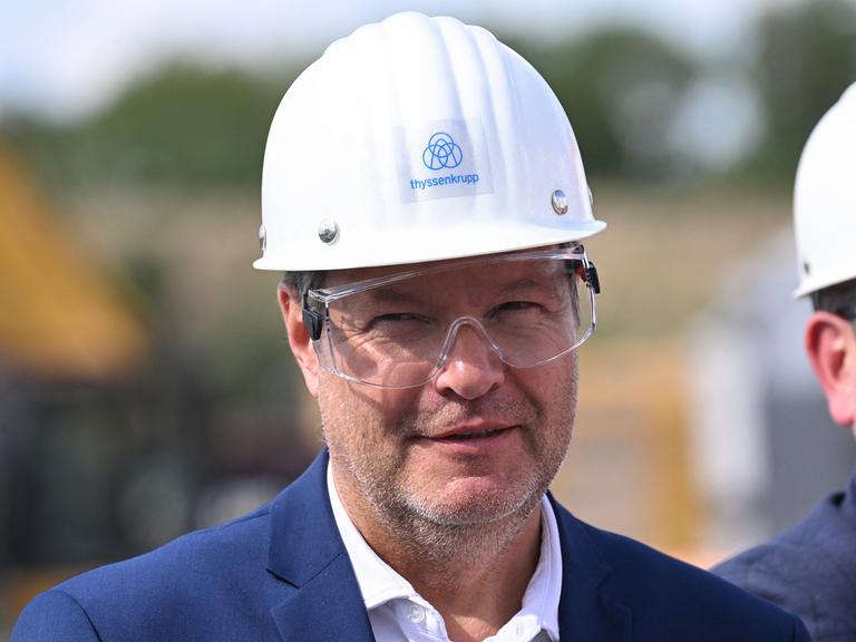 Der Bundesminister für Wirtschaft und Klimaschutz Robert Habeck mit einem Helm bei seinem Besuch bei der Thyssenkrupp-AG in Duisburg am 26. Juli 2023. Anlass des Besuchs ist das Fördersiegel der Bundesregierung für das Dekarbonisierungsprojekt "tkH2Steel".
