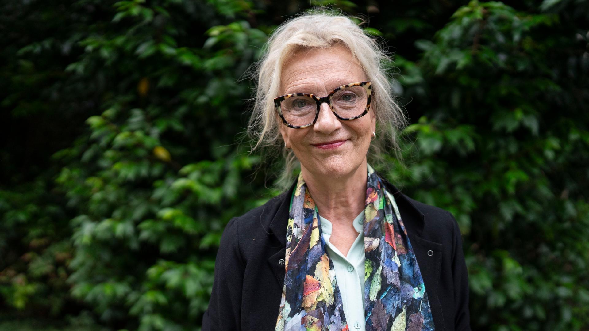 Elizabeth Strout trägt Brille, ein schwarzes Sakko und einem farbig gemusterten Schal und schaut freundlich in die Kamera. Elizabeth Strout trägt Brille, ein schwarzes Sakko und einem farbig gemusterten Schal und schaut freundlich in die Kamera.