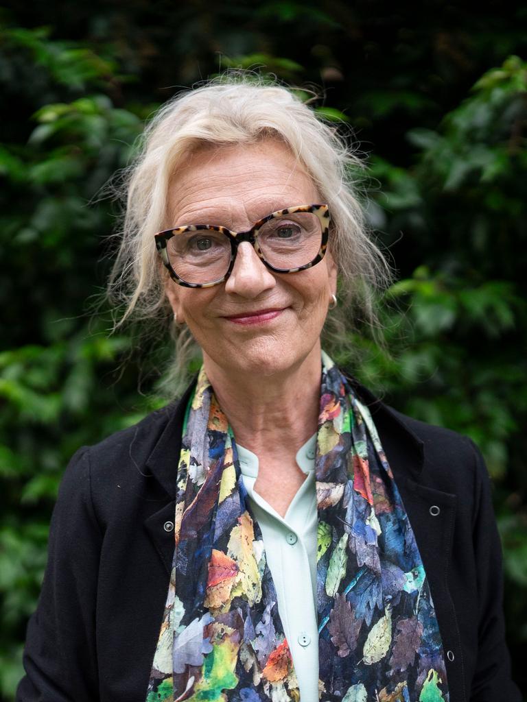 Elizabeth Strout trägt Brille, ein schwarzes Sakko und einem farbig gemusterten Schal und schaut freundlich in die Kamera.