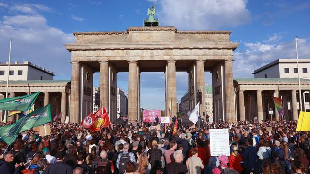 Viele Menschen stehen am Brandenburger Tor, einige halten Plakate. Auf einer Bühne steht "AfD stoppen".