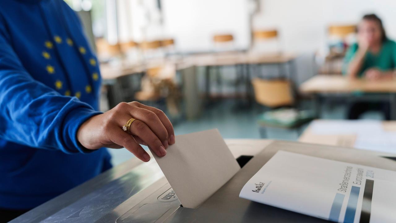Eine Frau mit Europa-Hoodie wirft ihren Stimmzettel in die Urne. 