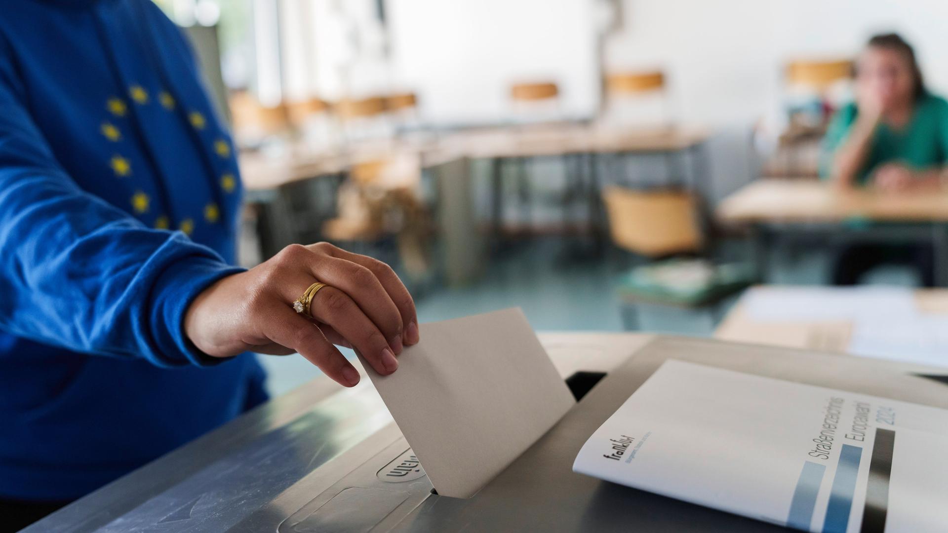 Eine Frau mit Europa-Hoodie wirft ihren Stimmzettel in die Urne. 