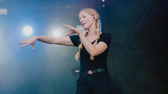 Cindy Klink steht auf einer Bühne und macht Gesten aus der Gebärden-Sprache.