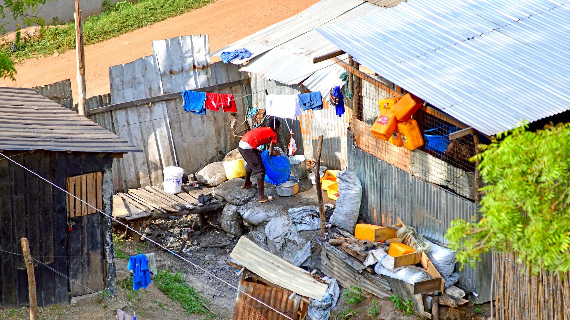 Blick in ein Wellblechgehöft in der südsudanesischen Hauptstadt Juba. Ein junger Mann reinigt eine Plastikwanne. Blick in ein Wellblechgehöft in der südsudanesischen Hauptstadt Juba. Ein junger Mann reinigt eine Plastikwanne.