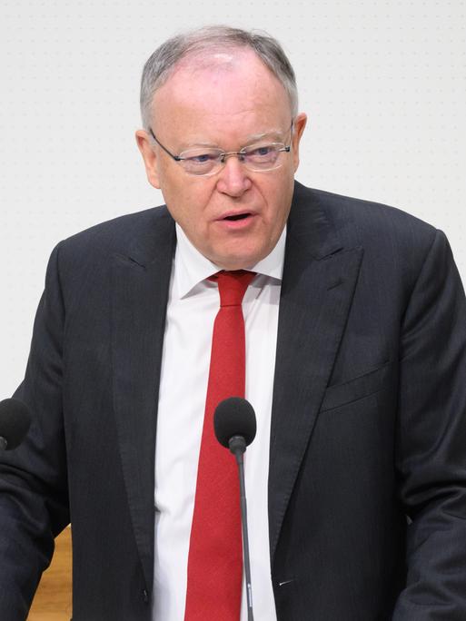 Stephan Weil (SPD), Ministerpräsident Niedersachsens, steht im dunklen Jacket, weißem Hemd und mit roter Krawatte an einem Rednerpult. 