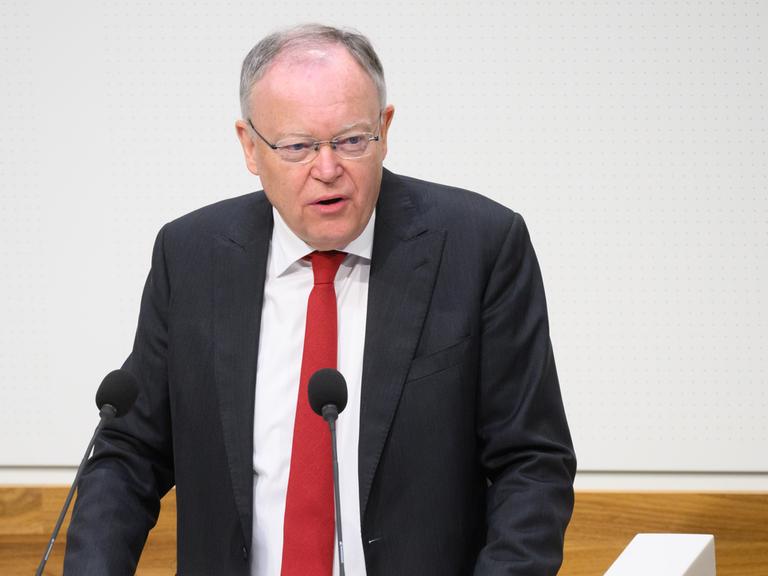 Stephan Weil (SPD), Ministerpräsident Niedersachsens, steht im dunklen Jacket, weißem Hemd und mit roter Krawatte an einem Rednerpult. 