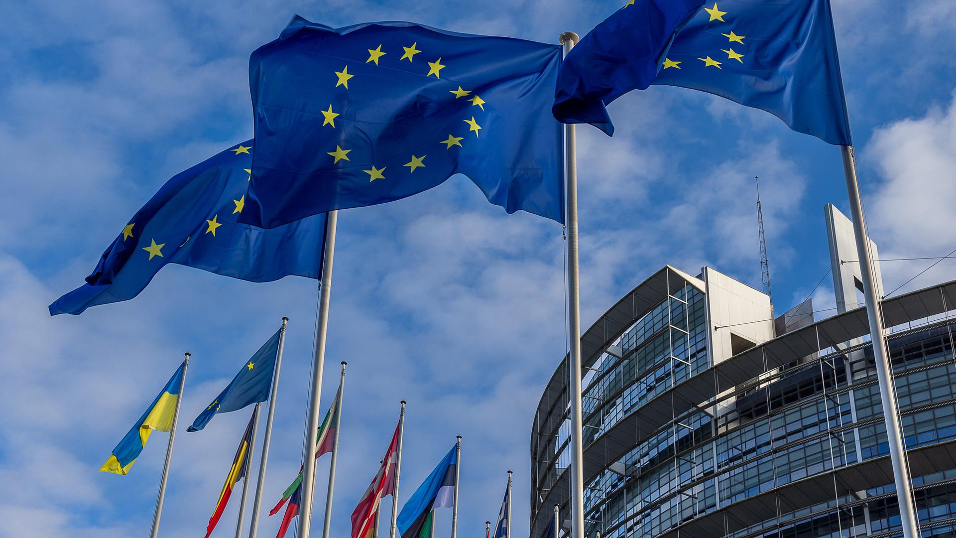 Drei Europaflaggen und mehrere Nationalflaggen wehen vor dem Gebäude des Europäischen Parlaments in Straßburg.