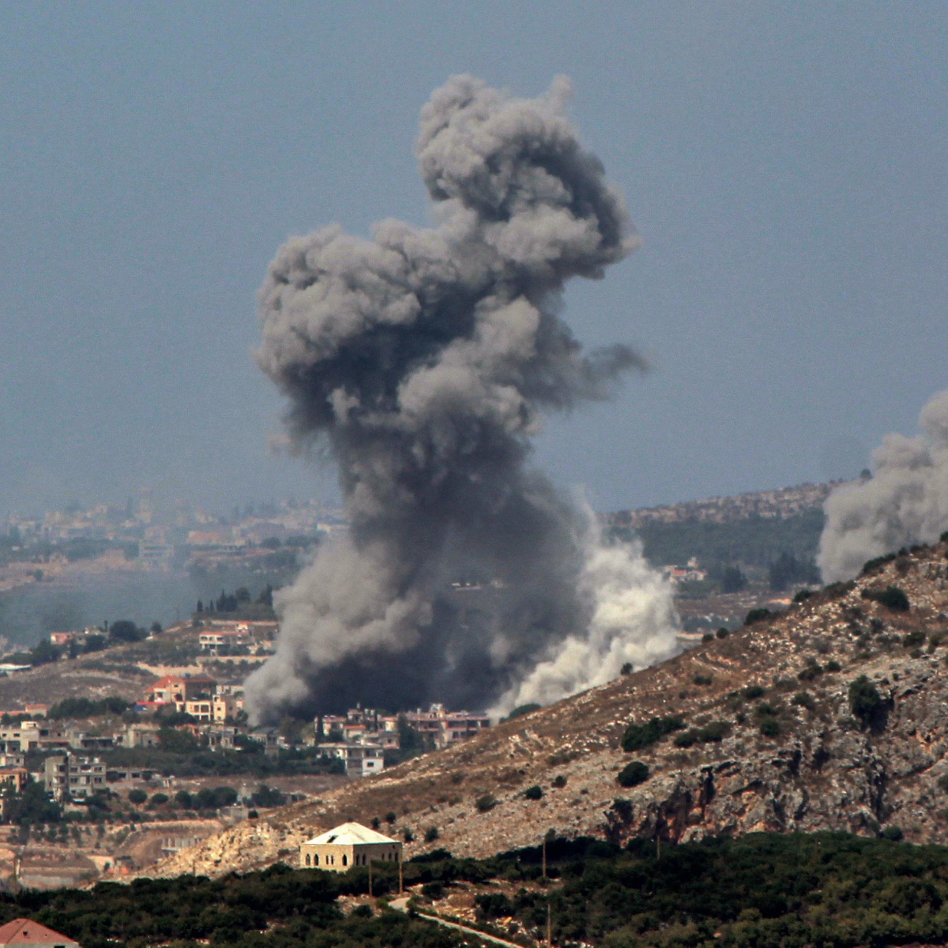Rauch steigt aus einem Dorf in den Bergen auf.