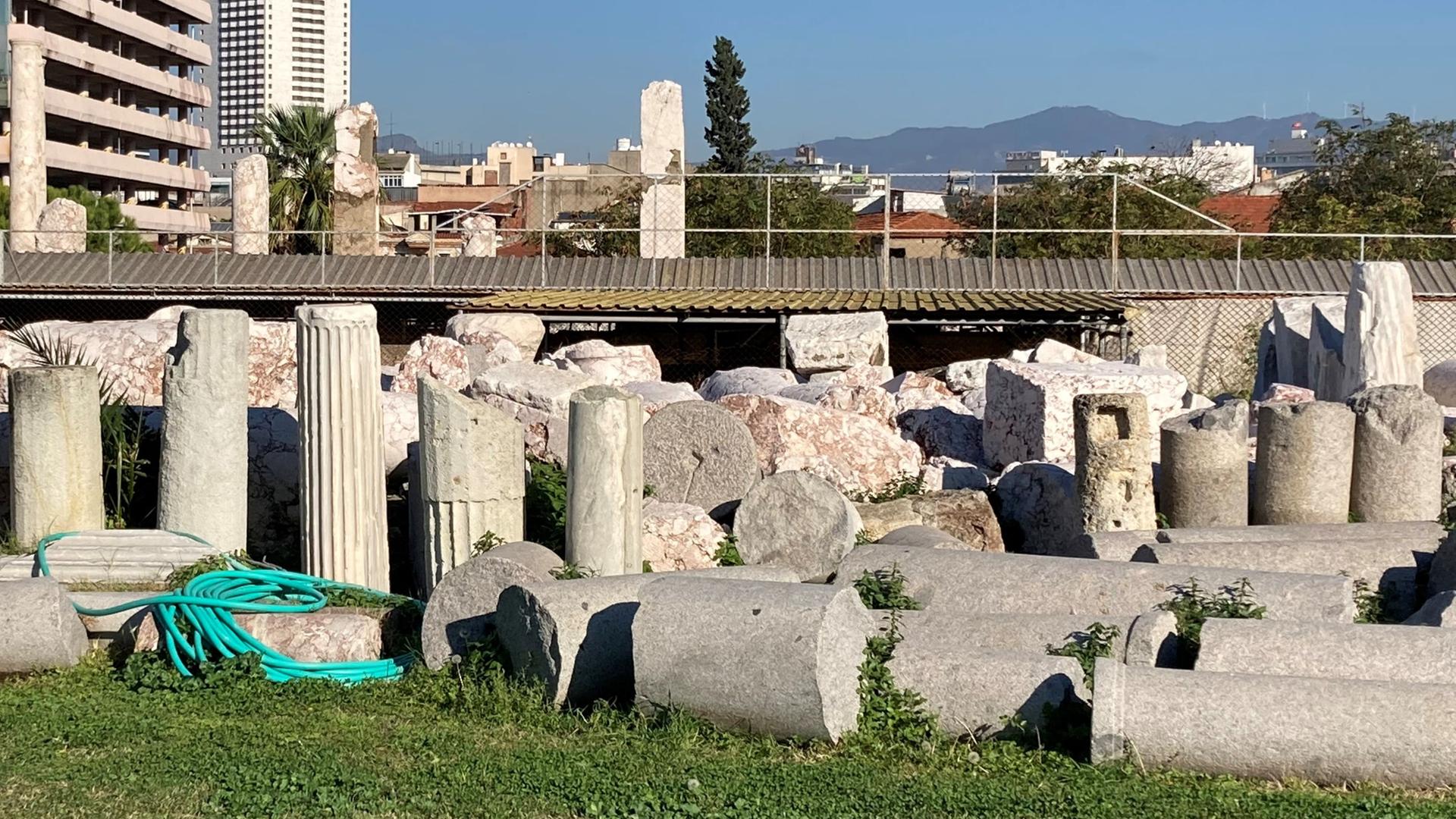 Blick auf alte Säulen vor einer Kulisser moderner Häuser in Izmir.