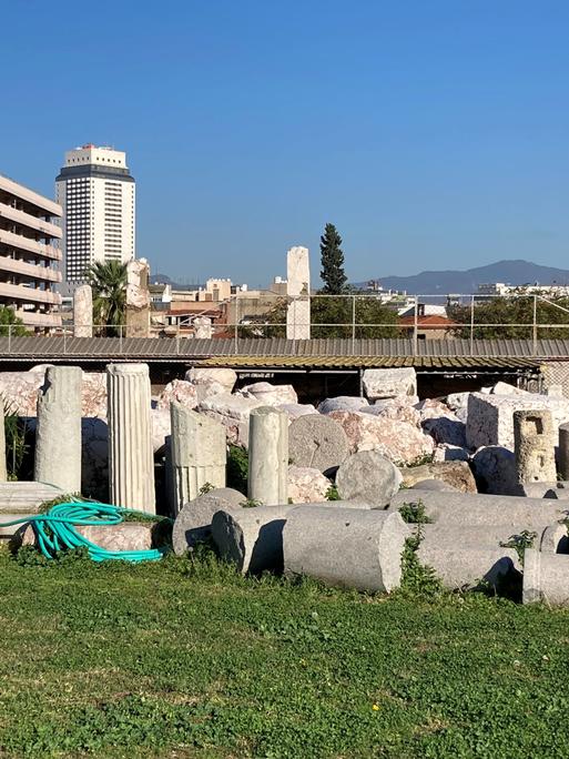 Blick auf alte Säulen vor einer Kulisser moderner Häuser in Izmir.