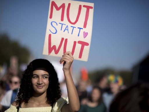 Junge Demonstrantin mit Plakat mit der Aufschrift Mut Statt Wut.