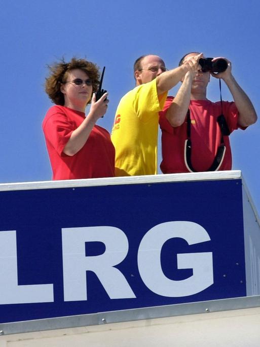 Mit Fernglas und Funkgerät ausgerüstet beobachten eine Rettungsschwimmerin und zwei Rettungsschwimmer einer DLRG-Staffel am 26. Juli 2001 den Strand von Kühlungsborn. 