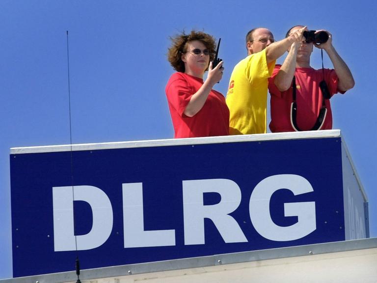 Mit Fernglas und Funkgerät ausgerüstet beobachten eine Rettungsschwimmerin und zwei Rettungsschwimmer einer DLRG-Staffel am 26. Juli 2001 den Strand von Kühlungsborn. 