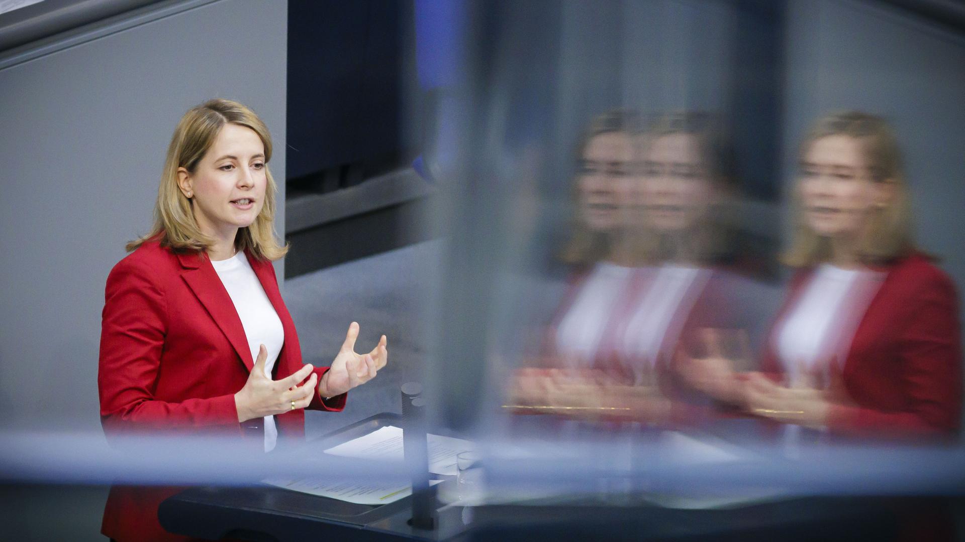 Verena Hubertz steht im Bundestag auf dem Podium und spricht. Sie hat schulterlanges bondes Haar und trägt einen roten Blazer.