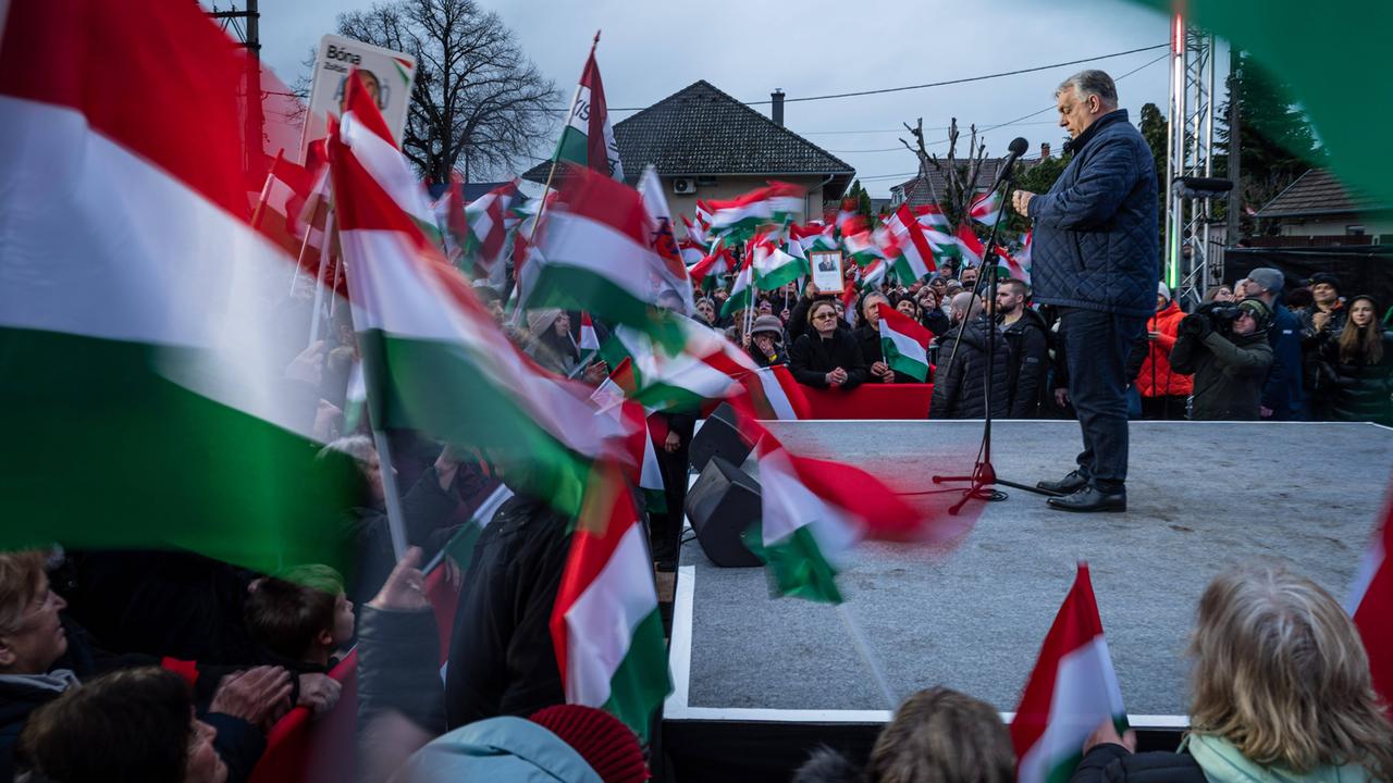 Ungarns Ministerpräsident Viktor Orbán steht auf einer Bühne während einer Wahlkampfveranstaltung. Es sind viele ungarische Fahnen zu sehen. Ungarns Ministerpräsident Viktor Orbán steht auf einer Bühne während einer Wahlkampfveranstaltung. Es sind viele ungarische Fahnen zu sehen.