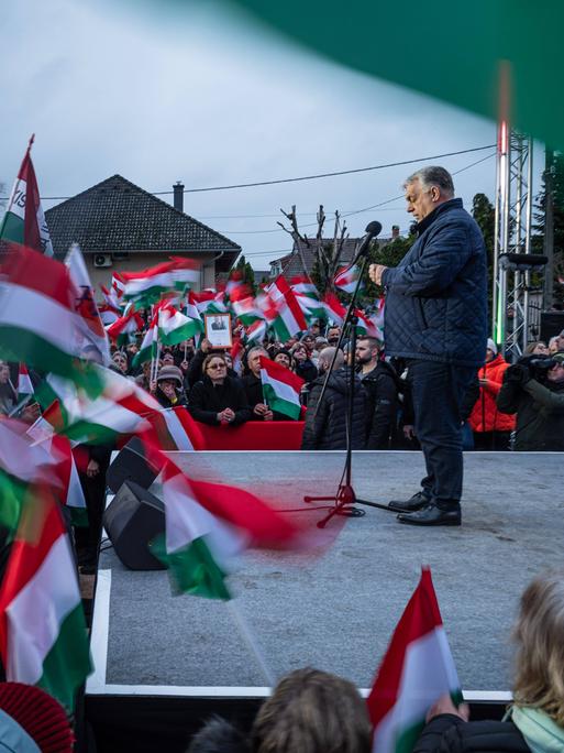 Ungarns Ministerpräsident Viktor Orbán steht auf einer Bühne während einer Wahlkampfveranstaltung. Es sind viele ungarische Fahnen zu sehen. 