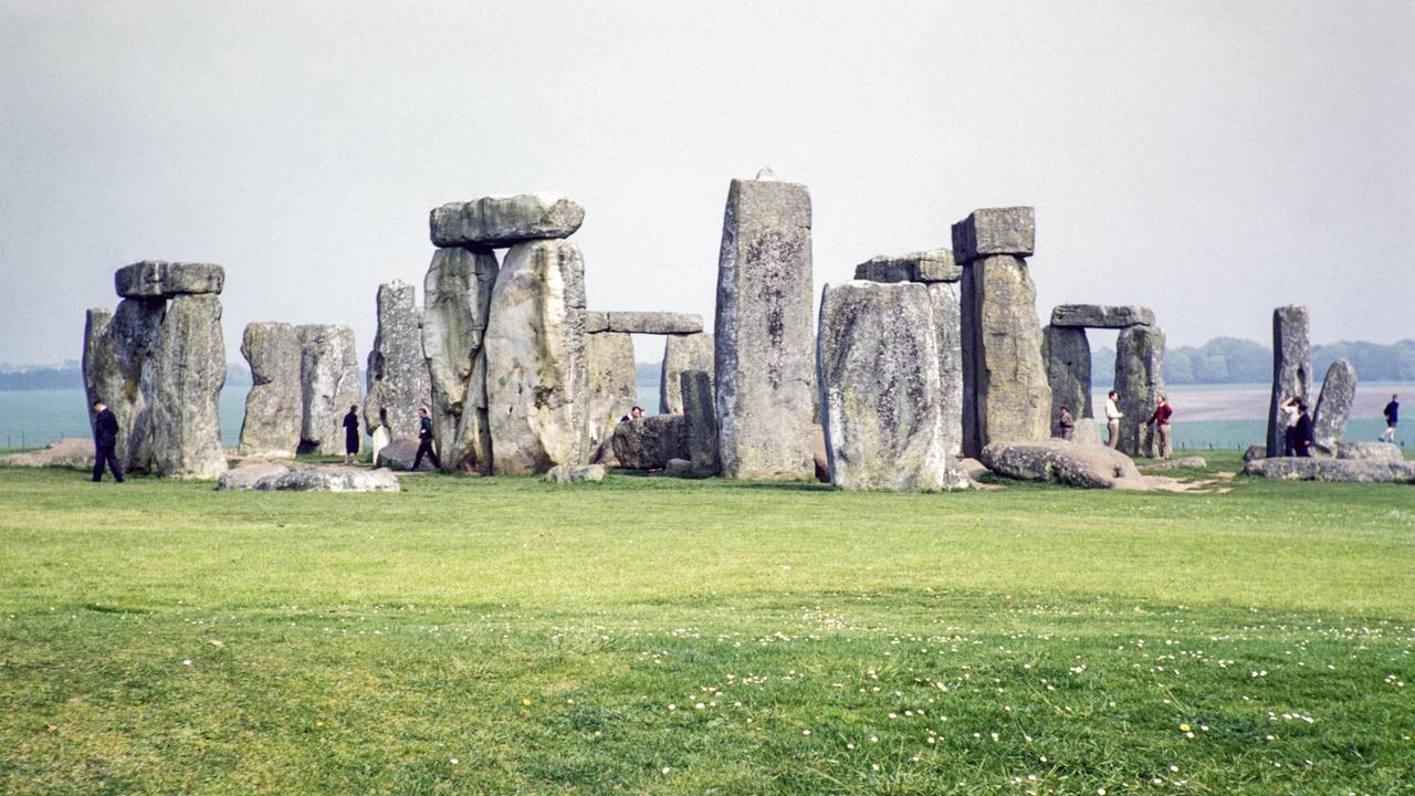 Menschen bei der Erkundung der stehenden Steine in der neolithischen Stätte Stonehenge, Wiltshire, England.