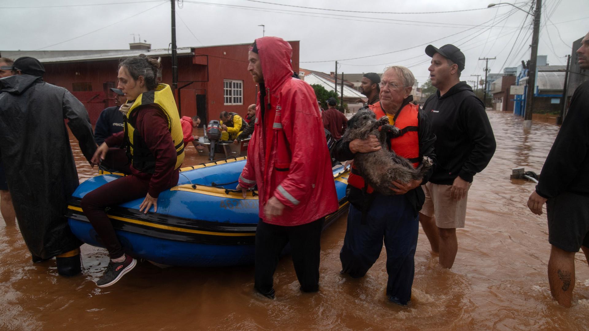 Menschen und ein Hund werden mit einem Boot in einer Überflutungsregion in Sicherheit gebracht. 
