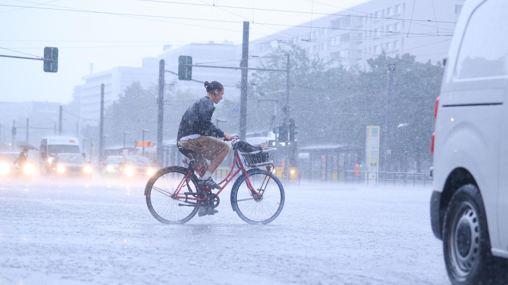 Ein Radfahrer fahren bei starkem Regen durch die Stadt.