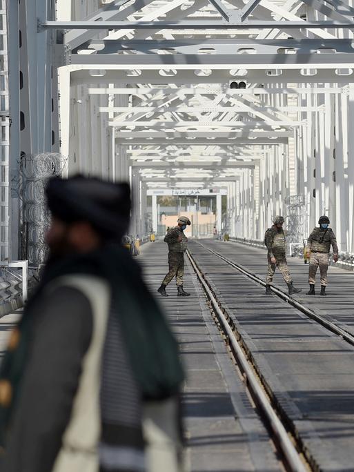 Uniformierte Grenzschutzbeamte kontrollieren die Einreise auf einer Stahlbrücke.