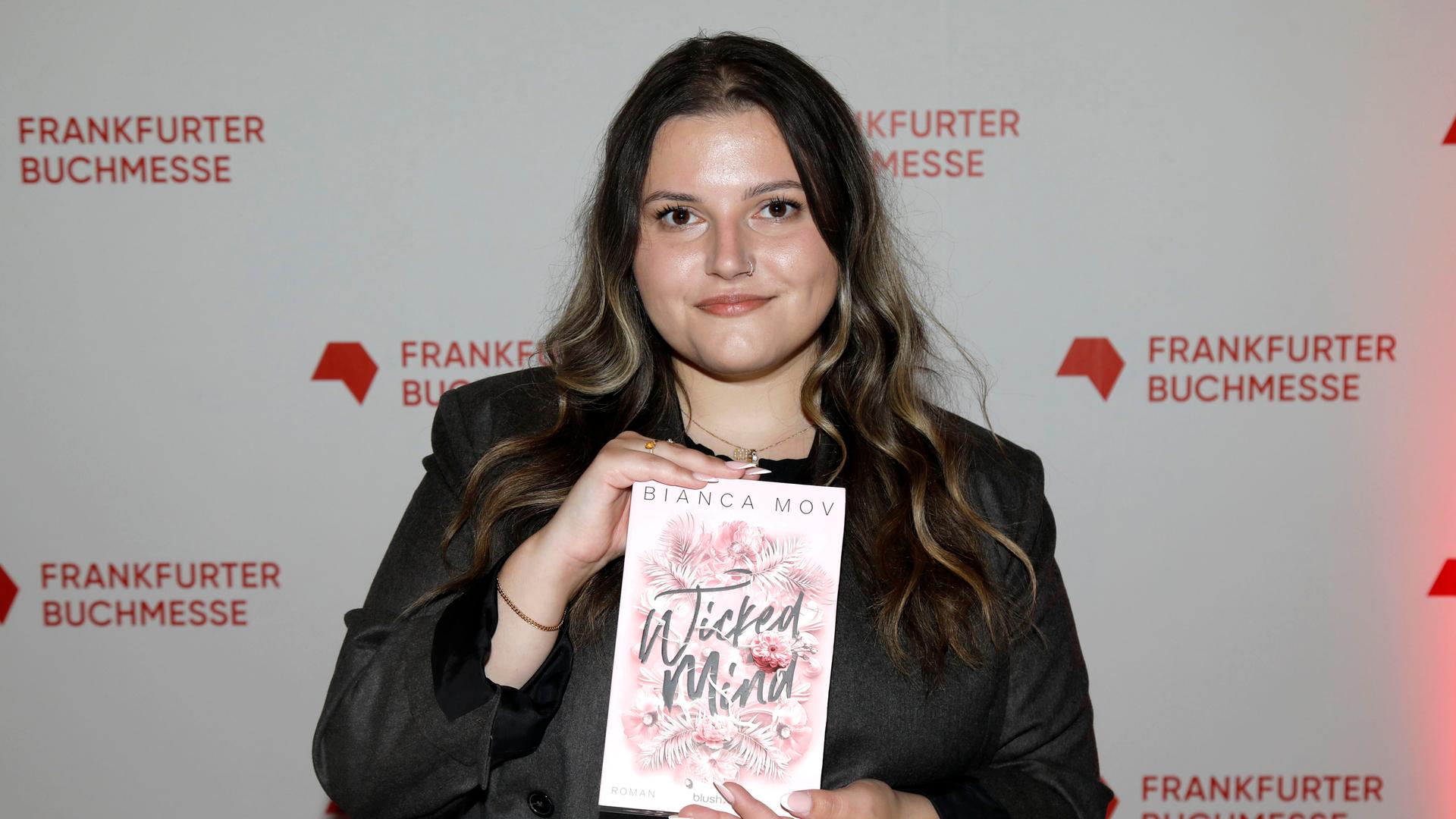 Bianca Mov hält ihr Buch "Wicked Mind" in die Kamera