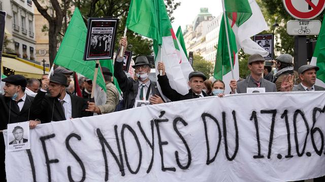 Eine Demonstration in Paris. Im Vordergrund ein Banner, auf dem in französischer Sprache "Den Ertrunkenen des 17.10.61" gedacht wird. Hinter dem Banner laufen Demonstrierende, teils in Grün-Weiß-Rot, den Farben Algeriens. Eine Demonstration in Paris. Im Vordergrund ein Banner, auf dem in französischer Sprache "Den Ertrunkenen des 17.10.61" gedacht wird. Hinter dem Banner laufen Demonstrierende, teils in Grün-Weiß-Rot, den Farben Algeriens.