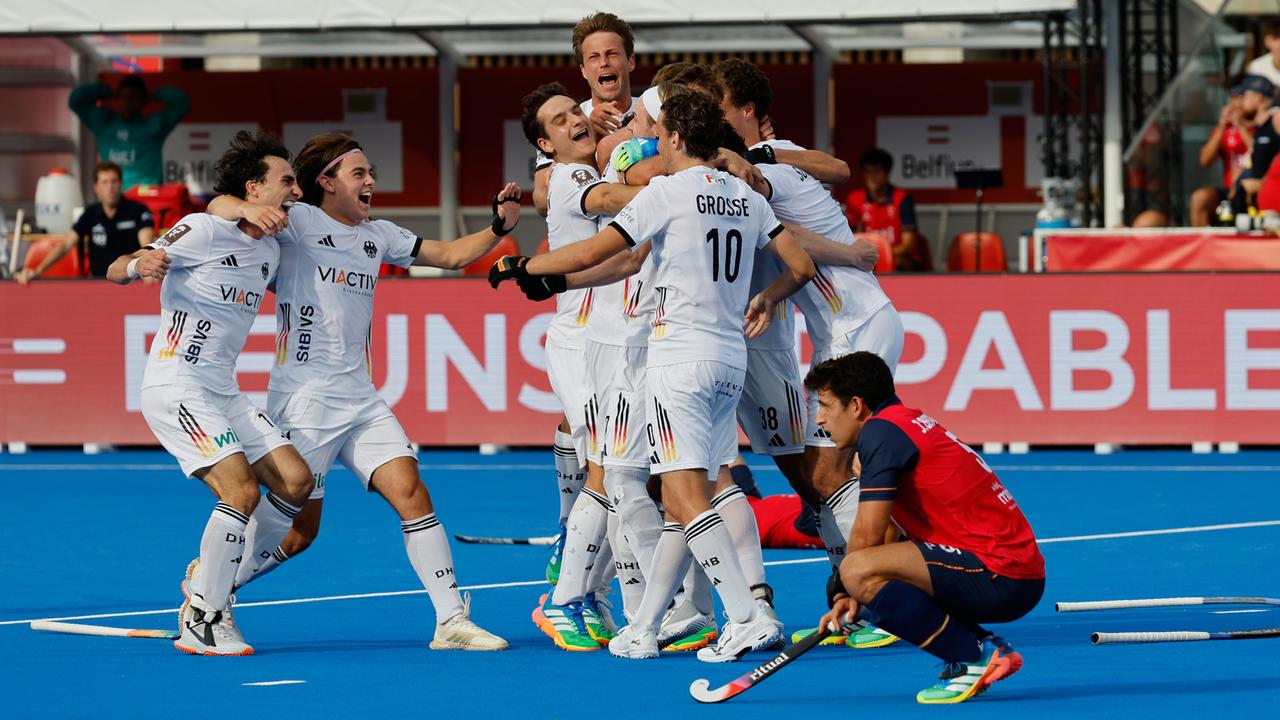 Deutsche Hockeyspieler sammeln sich zum Jubel und umarmen sich, im Vordergrund hockt ein spanischer Spieler niedergeschlagen am Boden.