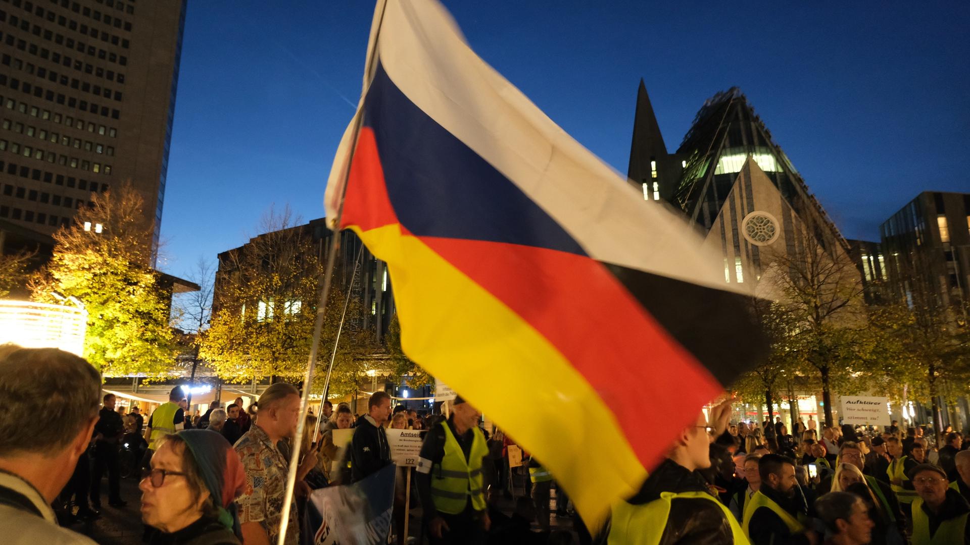 Teilnehmer einer Demonstration versammeln in Leipzig mit einer Fahne mit den russischen und deutschen Nationalfarben. 