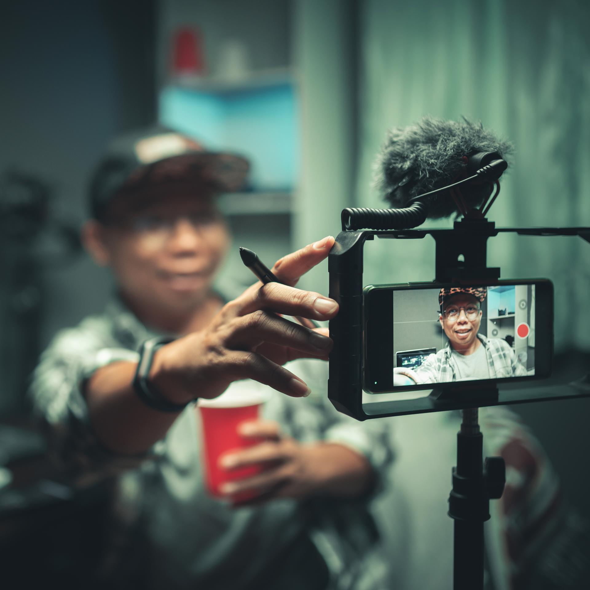 Ein Blogger streamt auf Tik Tok, er hält die Kamera vor sein Gesicht.