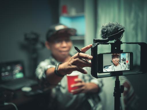 Ein Blogger streamt auf TikTok, er hält die Kamera vor sein Gesicht.