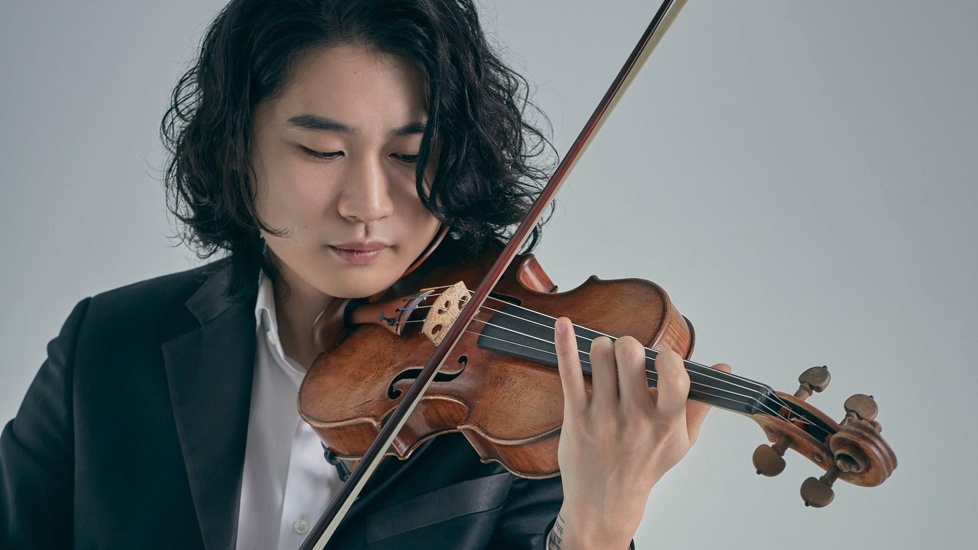 Der Geiger Inmo Yang spielt mit schulterlangem Haar seine Geige.
