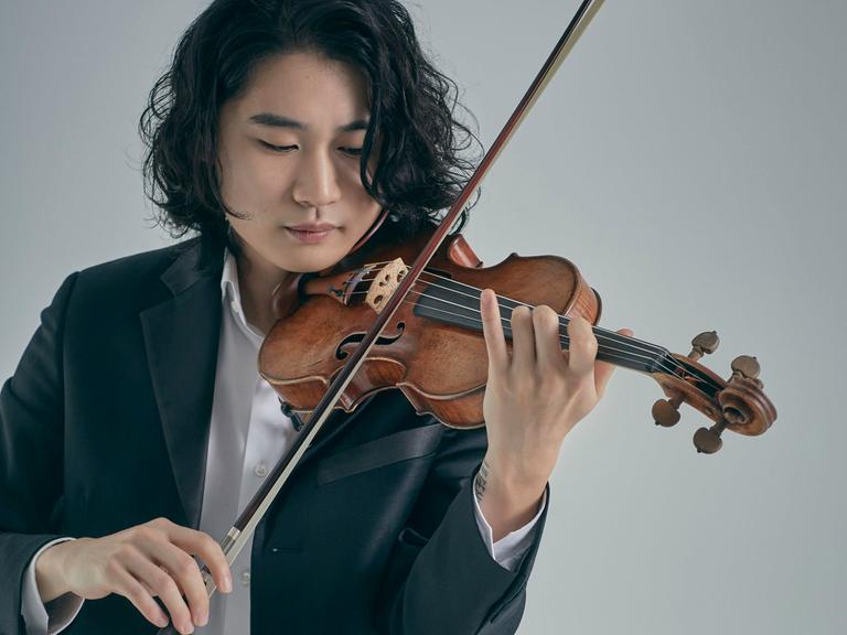 Der Geiger Inmo Yang spielt mit schulterlangem Haar seine Geige.
