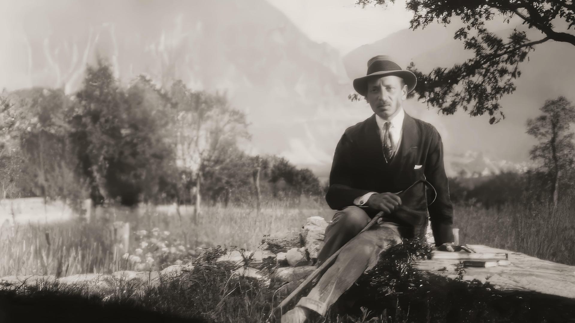 Rainer Maria Rilke auf einer historischen schwarz-weiß Aufnahme von 1924. Zu sehen ist eine Mann mit Stock und Hut auf einem Stein sitzend, neben ihm liegt ein Buch. Im Hintergrund schweizer Alpenpanorama von Château de Muzot. Rainer Maria Rilke auf einer historischen schwarz-weiß Aufnahme von 1924. Zu sehen ist eine Mann mit Stock und Hut auf einem Stein sitzend, neben ihm liegt ein Buch. Im Hintergrund schweizer Alpenpanorama von Château de Muzot.