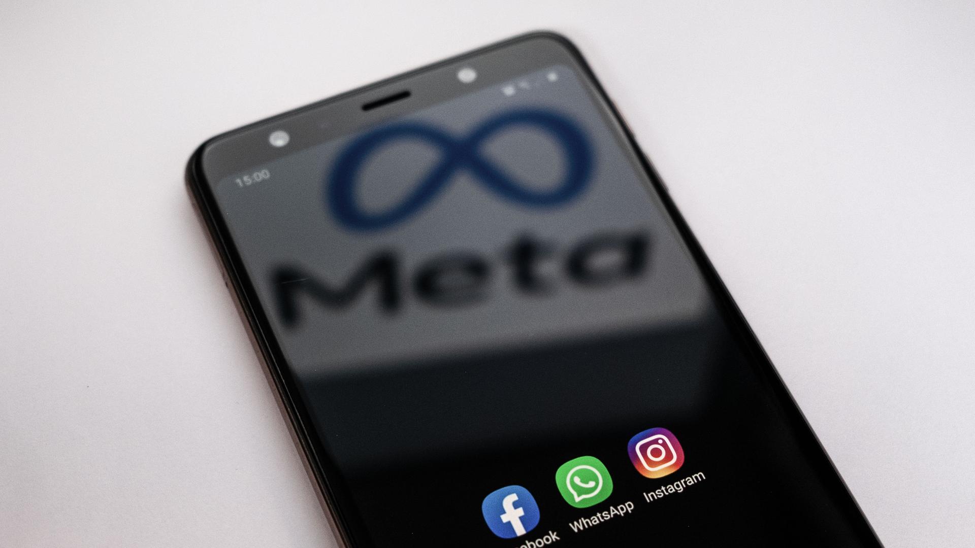 Auf einem Smartphone sind die Apps von Facebook, Whatsapp und Instagram zu sehen. Auf dem Bildschirm spiegelt sich der Schriftzug plus Logo von Meta. Auf einem Smartphone sind die Apps von Facebook, Whatsapp und Instagram zu sehen. Auf dem Bildschirm spiegelt sich der Schriftzug plus Logo von Meta.